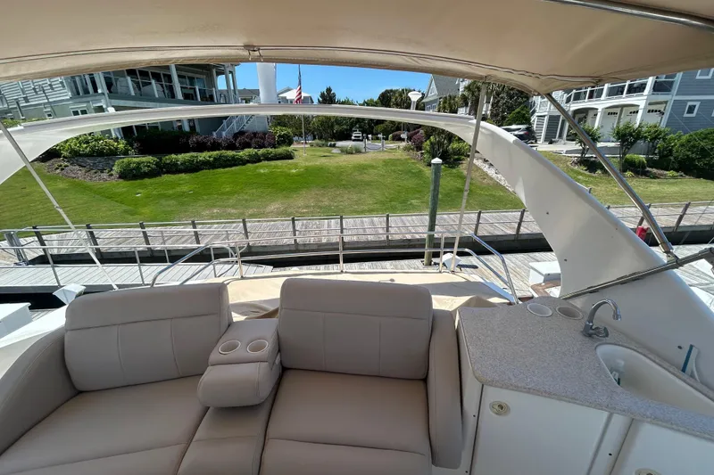Slide: The Image of 2001 Silverton 410 Sport Bridge yacht interior with seating and sink, docked near waterfront homes. - 12