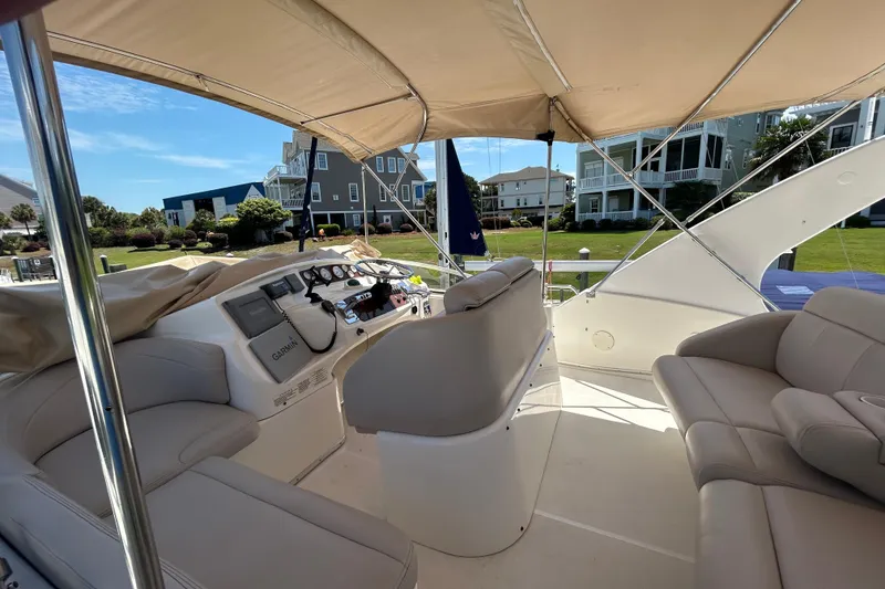 Slide: The Image of 2001 Silverton 410 Sport Bridge interior with helm, seating, and canopy, docked near waterfront homes. - 14