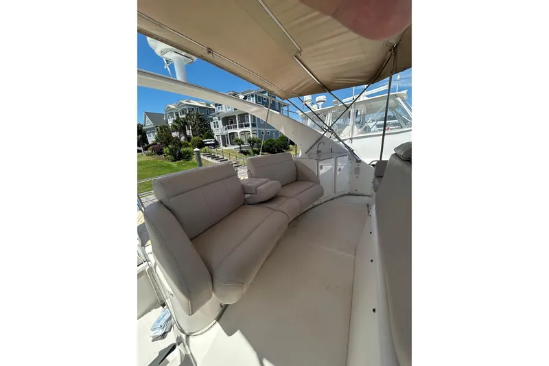 Slide: The Image of 2001 Silverton 410 Sport Bridge yacht with beige seating under canopy, docked near waterfront homes. - 15