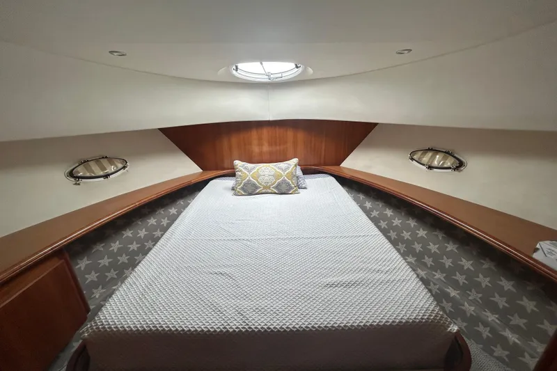 Slide: The Image of 2001 Silverton 410 Sport Bridge cabin interior with bed, portholes, and decorative pillow. - 19
