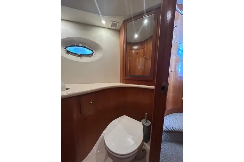 Slide: The Image of Bathroom interior of 2001 Silverton 410 Sport Bridge yacht with wooden cabinetry and porthole window. - 24