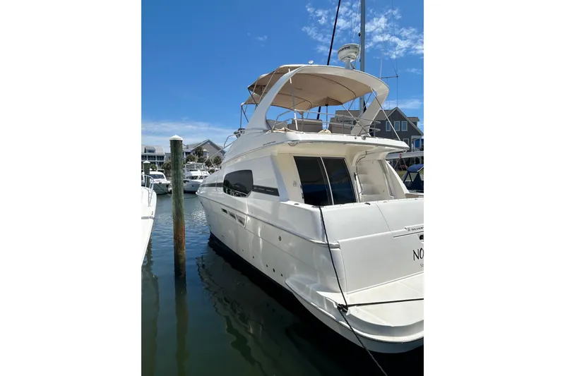 Slide: The Image of 2001 Silverton 410 Sport Bridge yacht docked in a marina under a clear blue sky. - 3