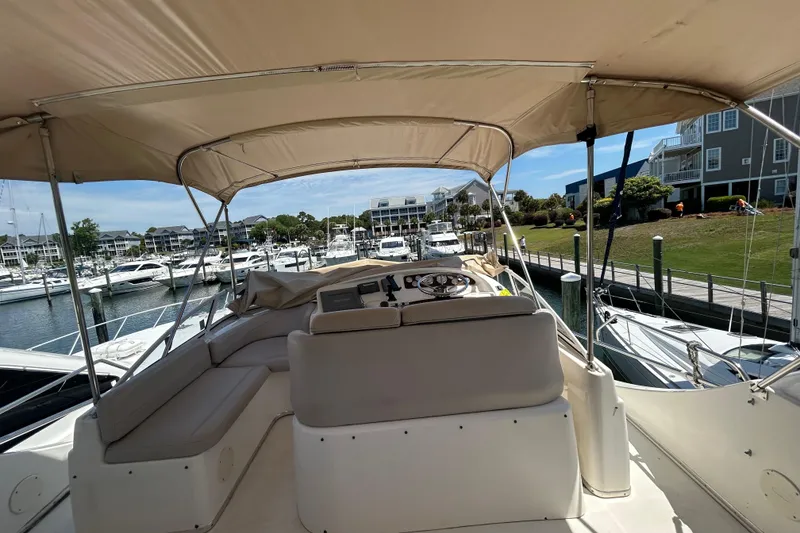Slide: The Image of 2001 Silverton 410 Sport Bridge yacht docked at marina, featuring spacious seating and helm under canopy. - 9