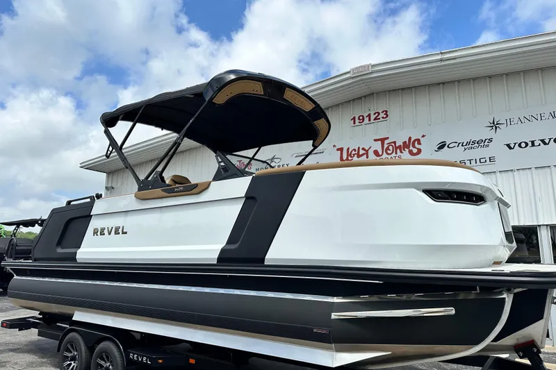 Slide: The Image of 2026 Revel RS25 boat with sleek design at dealership, under a partly cloudy sky. - 7