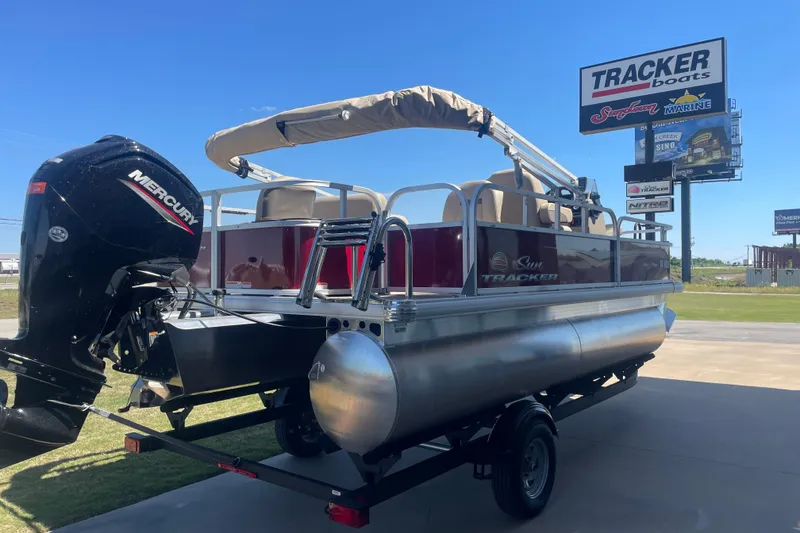 The Image of 2025 SUNTRACKER BASS BUGGY 18 pontoon boat with Mercury engine at dealership. - 1