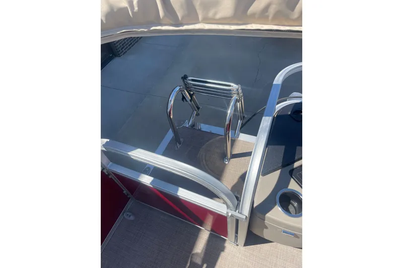 Slide: The Image of 2025 SUNTRACKER BASS BUGGY 18 boat ladder and deck area in sunlight. - 9