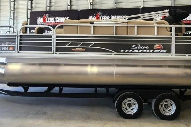 The Image of 2023 Sun Tracker Fishin' Barge 20 DLX pontoon boat on trailer in showroom. - 1