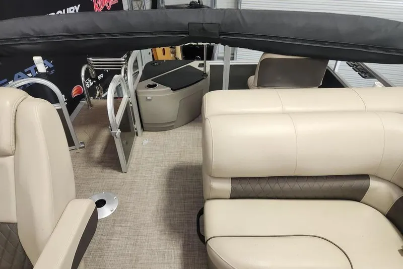Slide: The Image of 2023 Sun Tracker Fishin' Barge 20 DLX interior with beige seating and storage compartments. - 10