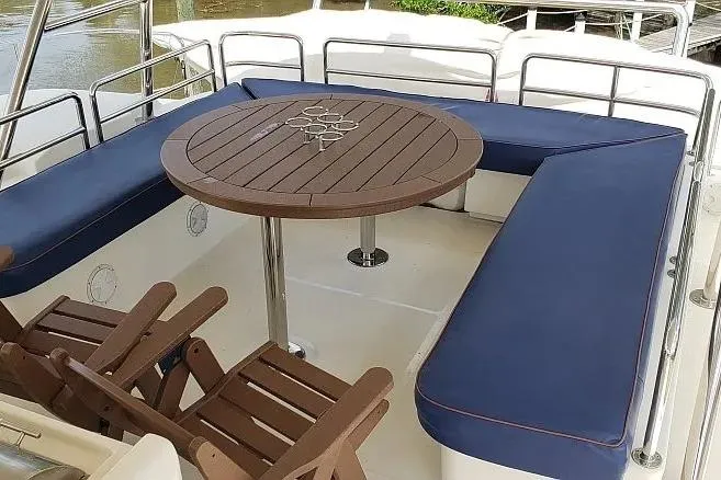 Slide: The Image of Outdoor seating area on 2014 Aquila 48 yacht with wooden table and blue cushions. - 8