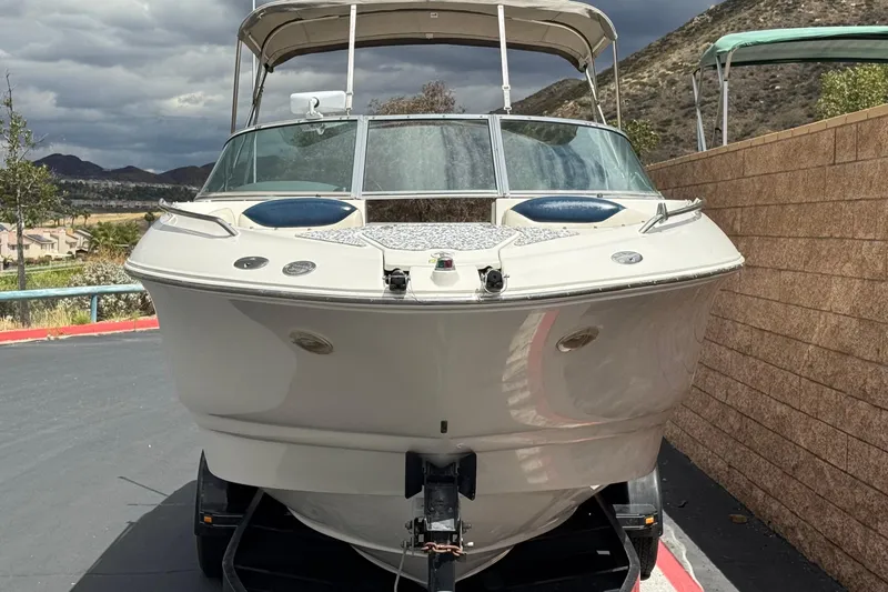 Slide: The Image of 2002 Monterey 248LS Montura Bowrider boat on trailer, parked near a brick wall. - 2