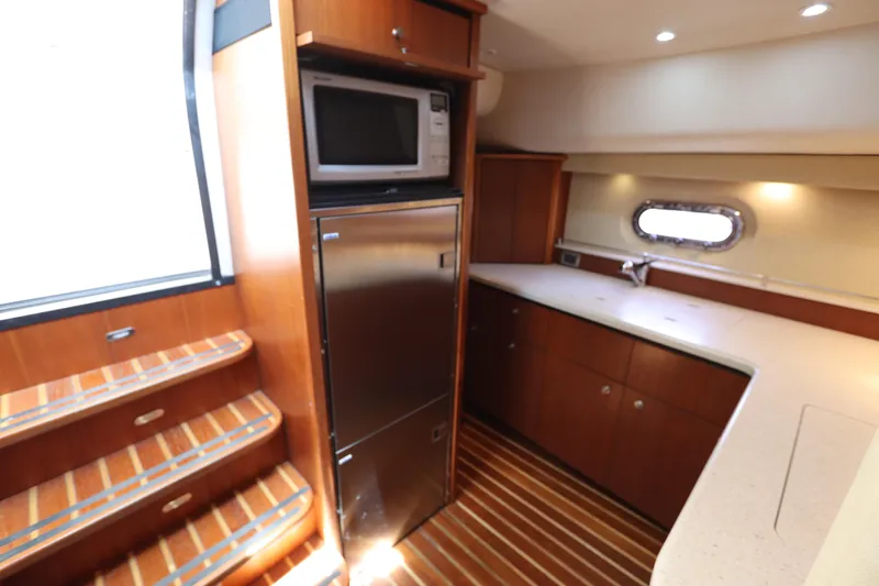 Slide: The Image of 2008 Tiara Yachts 4300 Sovran interior kitchen with wood cabinetry and stainless steel appliances. - 52