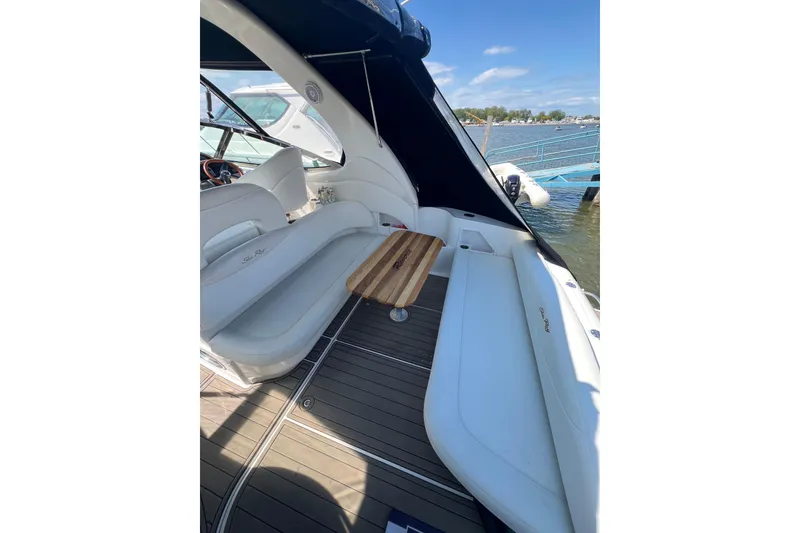 Slide: The Image of 2003 Sea Ray 360 Sundancer interior with seating and wooden table, docked by the water. - 18