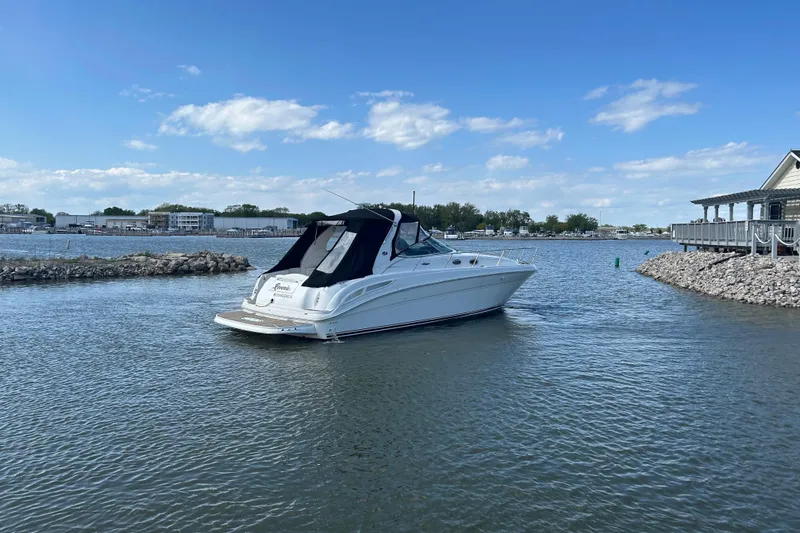 Slide: The Image of 2003 Sea Ray 360 Sundancer yacht on calm waters near a marina. - 2