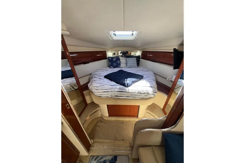 Slide: The Image of Cozy cabin interior of 2003 Sea Ray 360 Sundancer with plush bedding and elegant wood accents. - 24