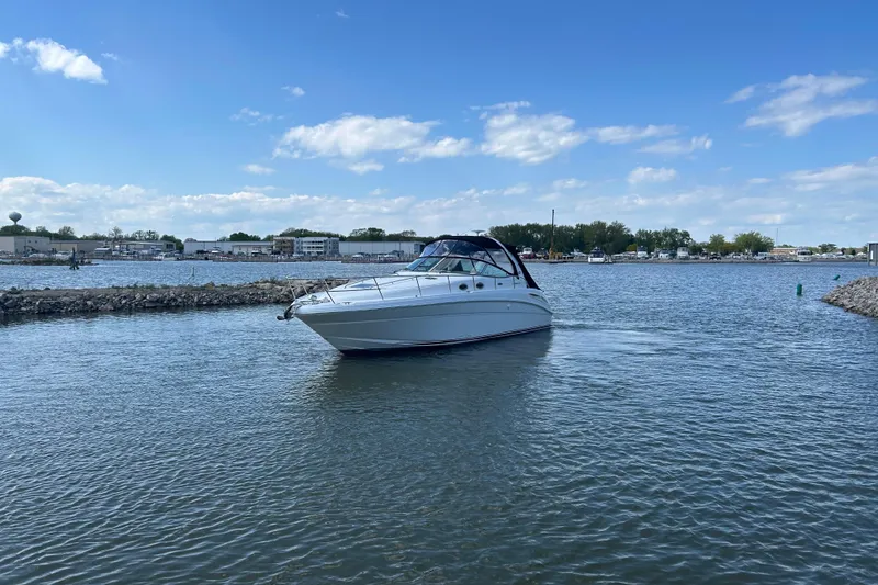 Slide: The Image of 2003 Sea Ray 360 Sundancer cruising on a calm lake under a clear blue sky. - 6
