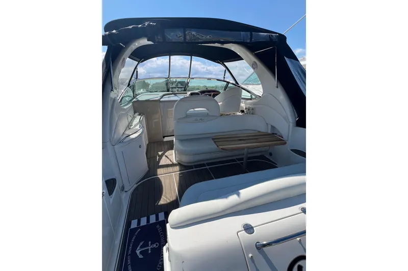 Slide: The Image of 2003 Sea Ray 360 Sundancer interior with seating and table, under a canopy, on open water. - 9