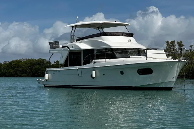 The Image of 2019 Beneteau Swift Trawler 47 anchored on calm water under a cloudy sky. - 0