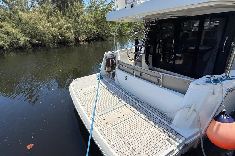 Slide: The Image of 2019 Beneteau Swift Trawler 47 docked, showcasing spacious rear deck and serene water surroundings. - 11
