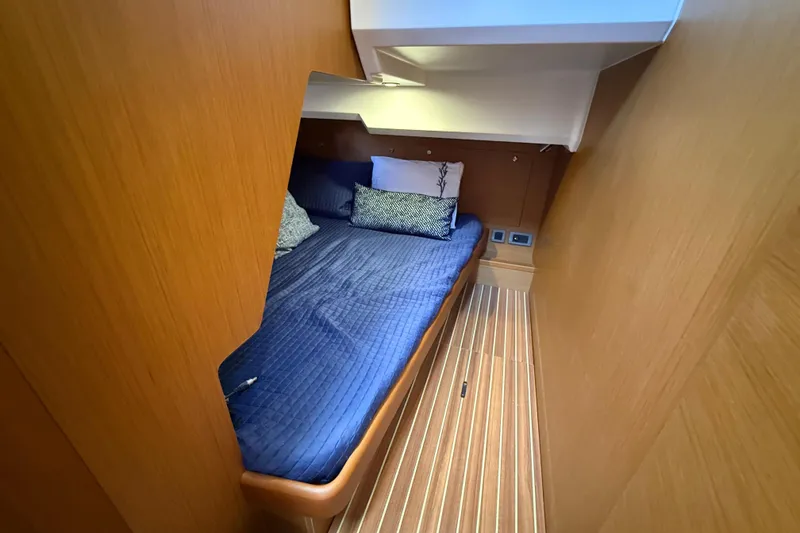 Slide: The Image of 2019 Beneteau Swift Trawler 47 cabin with blue bedding and wooden interior. - 18