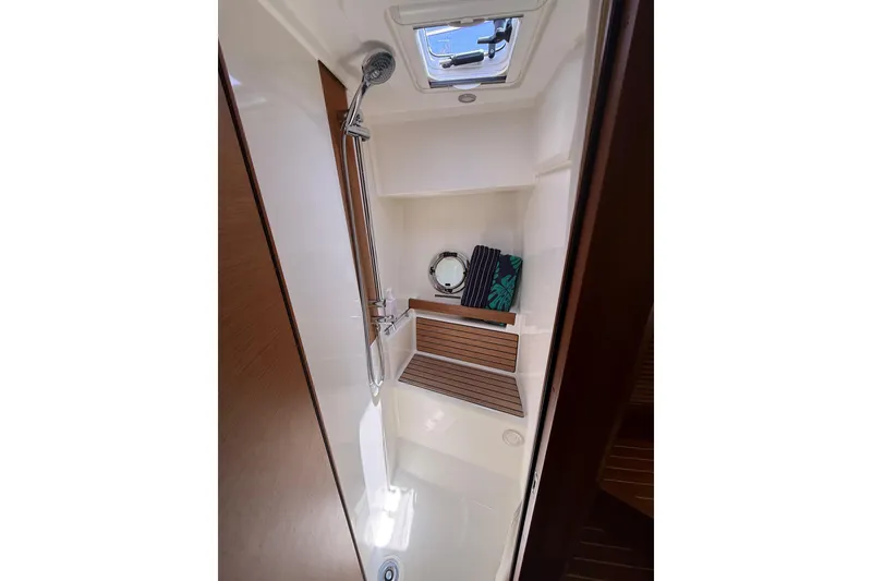 Slide: The Image of 2019 Beneteau Swift Trawler 47 shower area with wooden bench and porthole window. - 22