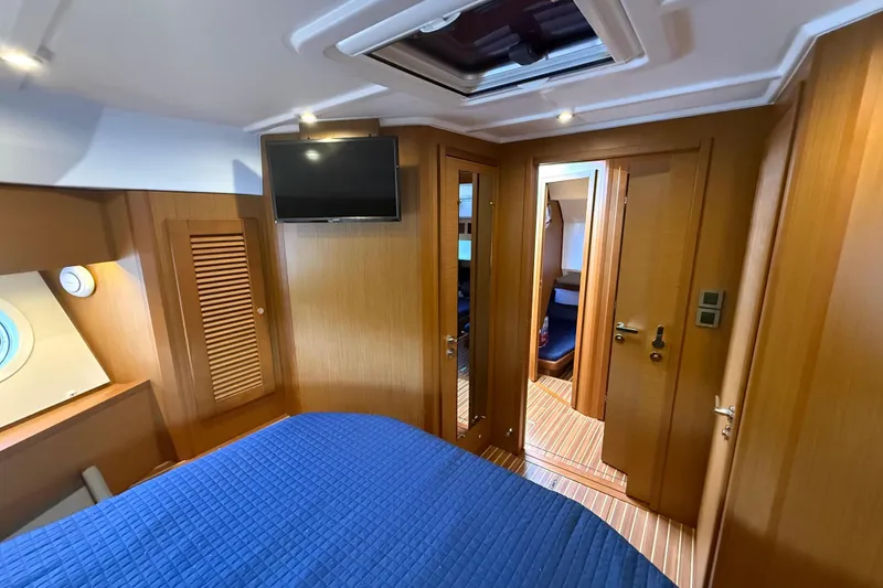 Slide: The Image of Luxurious cabin interior of 2019 Beneteau Swift Trawler 47 with wood paneling and blue bedding. - 23