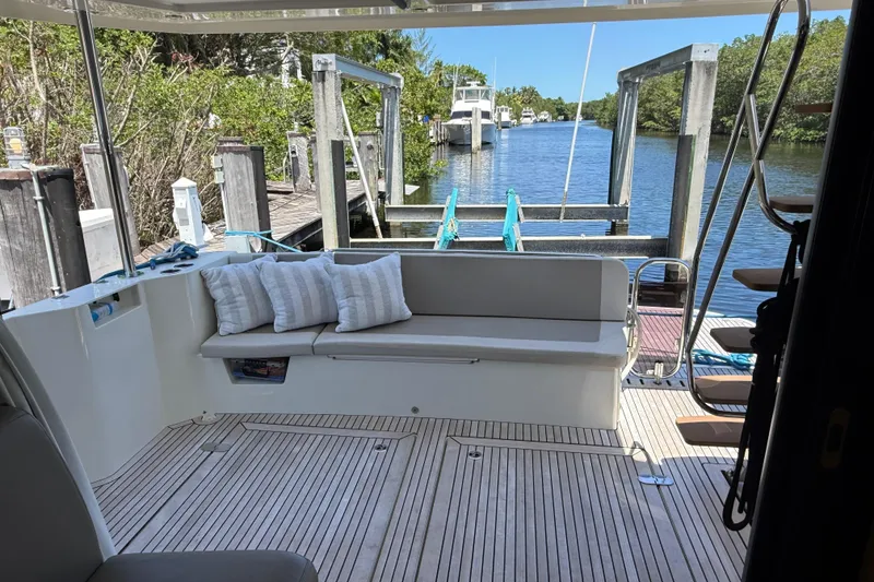 Slide: The Image of 2019 Beneteau Swift Trawler 47 deck with seating, docked by a serene waterway. - 6