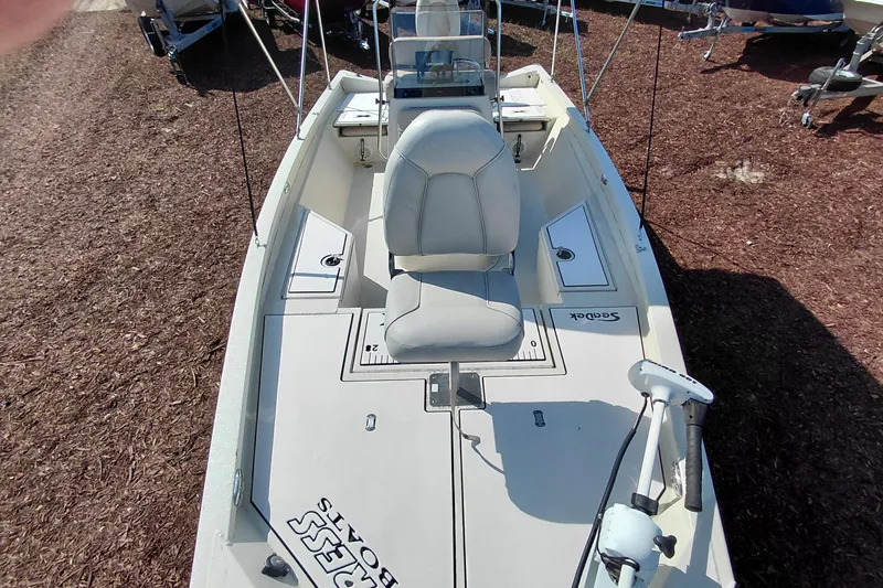 Slide: The Image of 2016 Express 20 BAY boat interior with seating and controls, parked on mulch. - 15