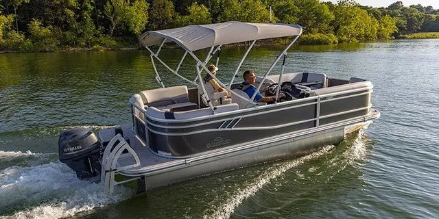 The Image of 2025 SunCatcher 20RC pontoon boat cruising on a serene lake. - 1