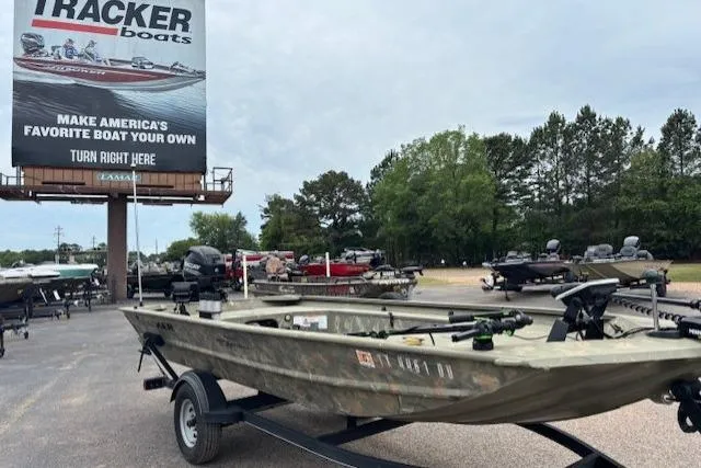 The Image of 2017 Tracker Grizzly 1654 MVX Sportsman boat on trailer near dealership billboard. - 0