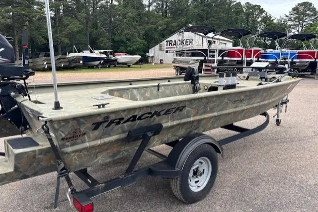 Slide: The Image of 2017 Tracker Grizzly 1654 MVX Sportsman boat on trailer, parked outdoors near other boats. - 2