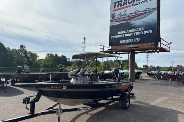The Image of 2013 Tracker Super Guide V-16 SC boat on trailer at dealership with billboard in background. - 0