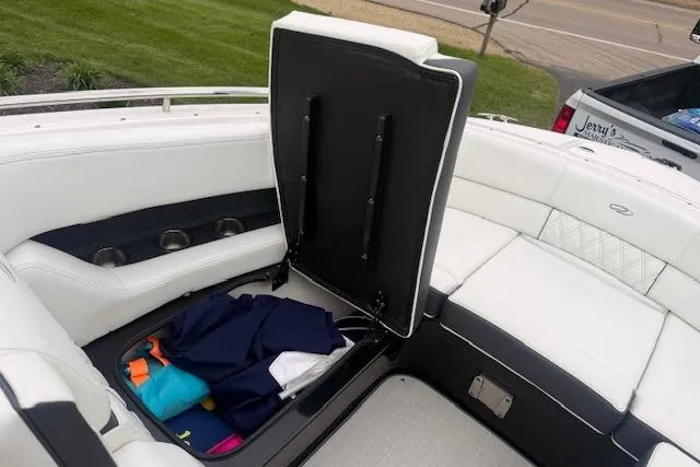 Slide: The Image of 2021 Regal 2800 Bowrider boat with open storage compartment, white seating, and colorful items inside. - 21