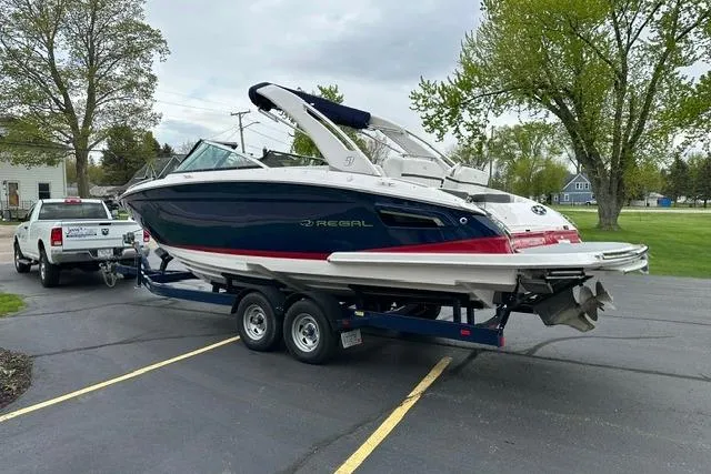 Slide: The Image of 2021 Regal 2800 Bowrider boat on trailer, parked outdoors near trees and a truck. - 38