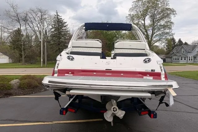 Slide: The Image of 2021 Regal 2800 Bowrider boat parked on pavement, rear view with trees in background. - 39