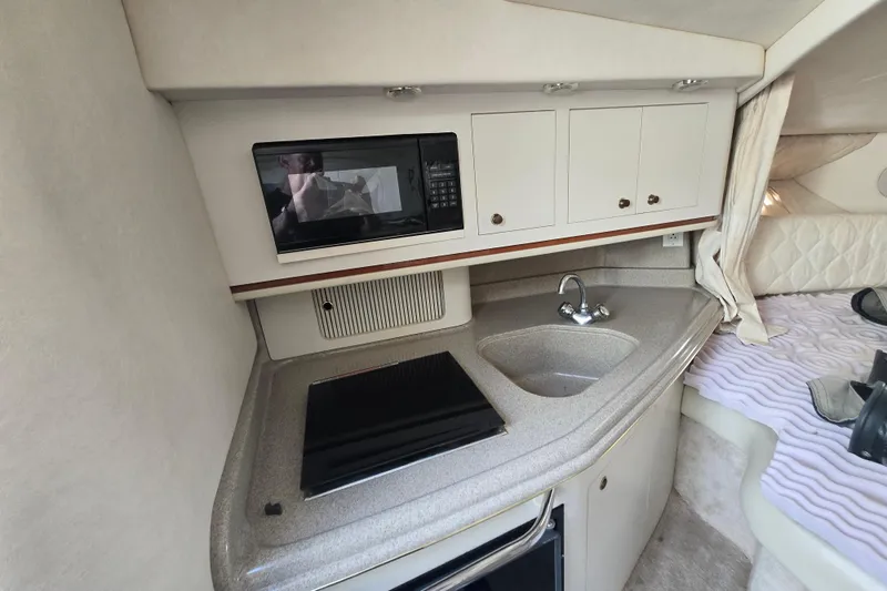 Slide: The Image of 2000 Sea Ray 290 Amberjack cabin kitchen with microwave, sink, and stove. - 14