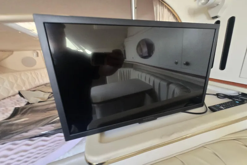 Slide: The Image of Flat-screen TV inside 2000 Sea Ray 290 Amberjack cabin, with remote control nearby. - 22
