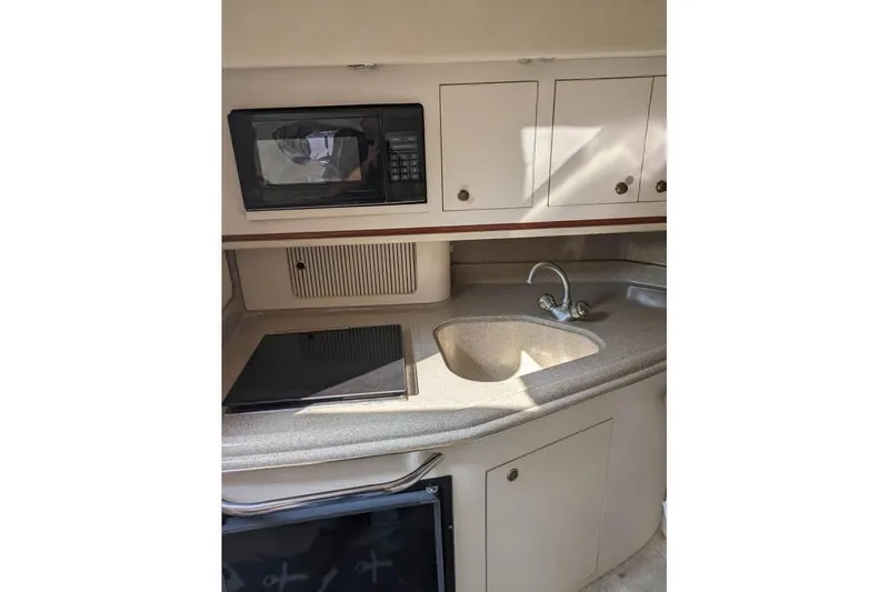 Slide: The Image of 2000 Sea Ray 290 Amberjack boat kitchen with microwave, sink, and storage cabinets. - 35