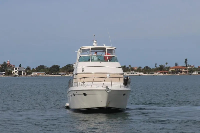 Slide: The Image of 2005 Carver 46 Voyager yacht on calm water near coastal homes. - 20
