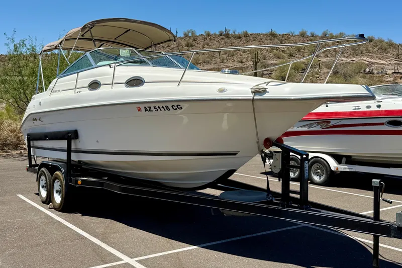 The Image of 1996 Sea Ray 250 Sundancer boat on trailer in sunny parking lot. - 1