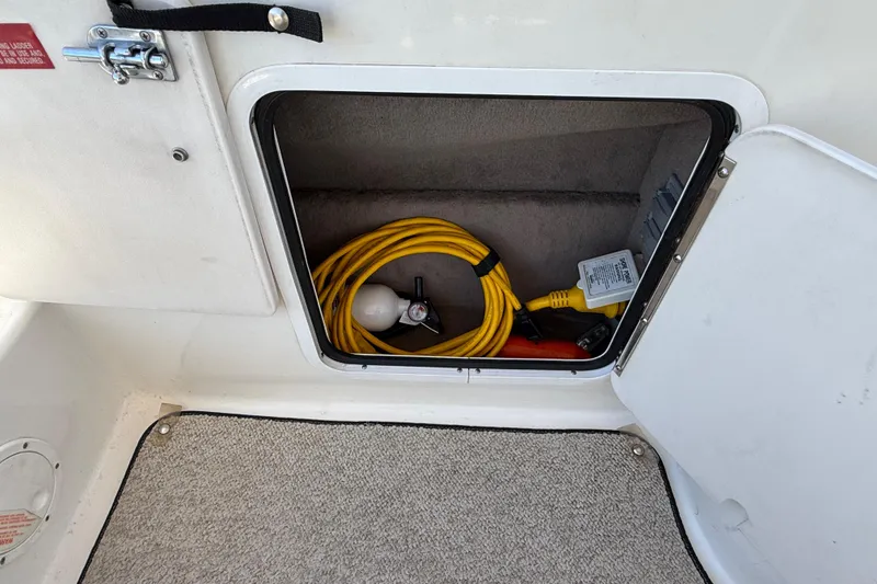 Slide: The Image of Storage compartment on a 1996 Sea Ray 250 Sundancer with yellow cable and accessories. - 18