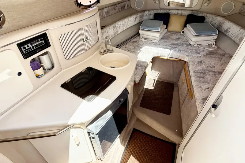 Slide: The Image of 1996 Sea Ray 250 Sundancer cabin interior with kitchenette and cozy sleeping area. - 20