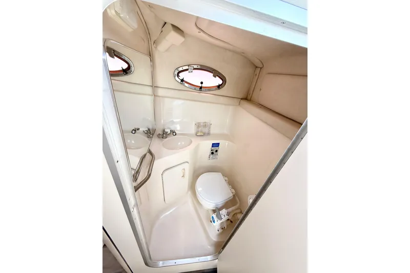 Slide: The Image of 1996 Sea Ray 250 Sundancer boat bathroom with sink, toilet, and porthole windows. - 28
