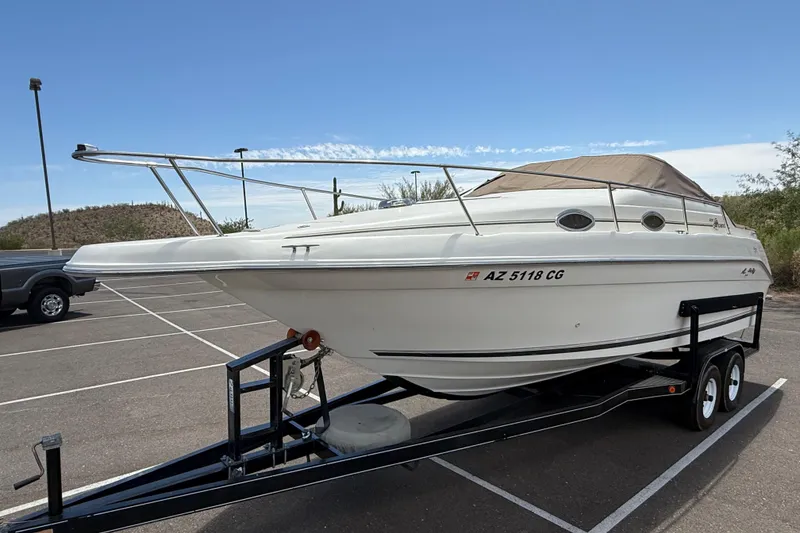 Slide: The Image of 1996 Sea Ray 250 Sundancer boat on trailer in parking lot under clear sky. - 33