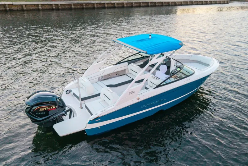 Slide: The Image of 2024 Regal LX2 boat with Yamaha engine, blue canopy, cruising on calm water. - 2