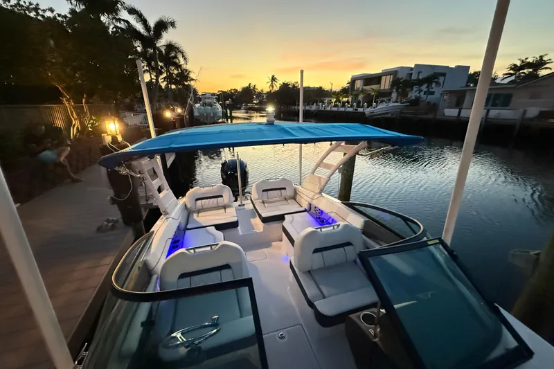 Slide: The Image of 2024 Regal LX2 boat docked at sunset, featuring a blue canopy and illuminated seating. - 27