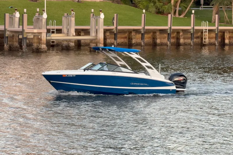 Slide: The Image of 2024 Regal LX2 boat cruising on a calm waterway near a dock. - 4