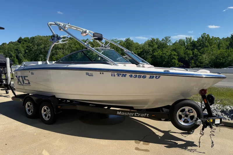 The Image of 2006 MasterCraft X-15 boat on trailer, parked outdoors under clear blue sky. - 0