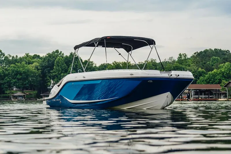 Slide: The Image of Manufacturer Provided Image: 2025 Bayliner D22I boat on calm lake with lush green shoreline. - 2
