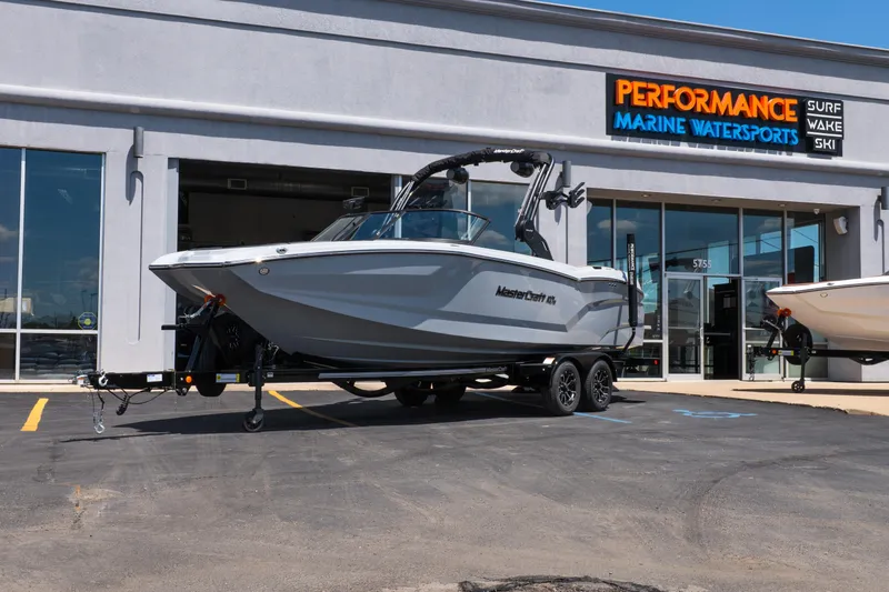 The Image of 2026 MasterCraft NXT24 boat on trailer outside Performance Marine Watersports dealership. - 1