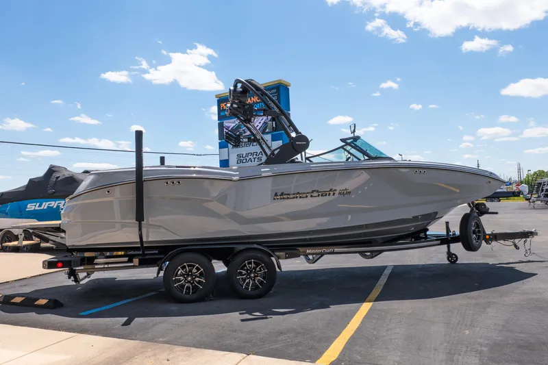 Slide: The Image of 2026 MasterCraft NXT24 boat on trailer in parking lot under clear sky. - 10